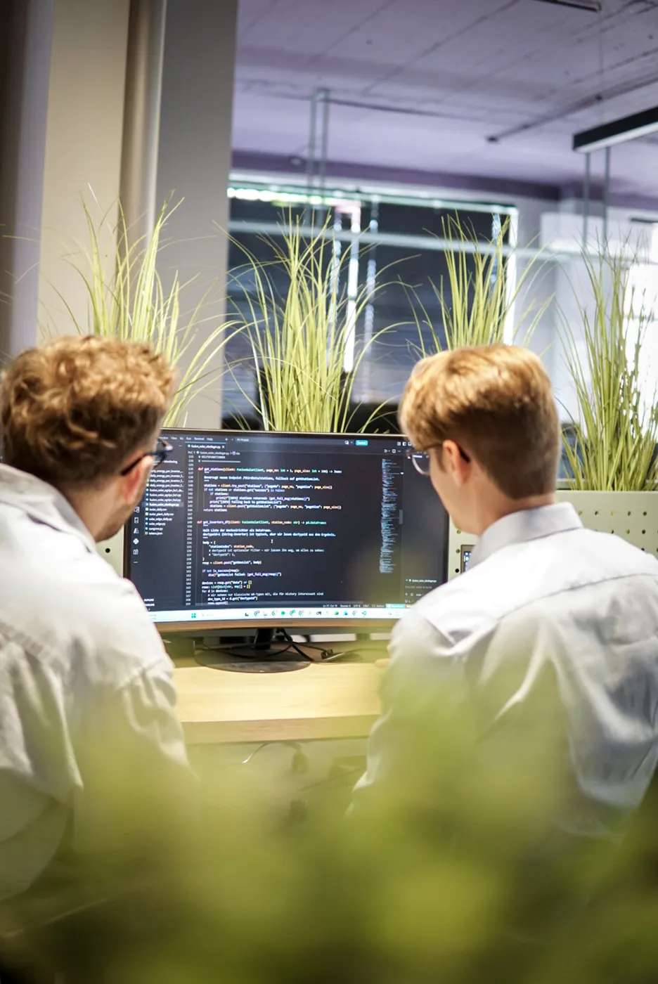 Two twinalps engineers reading through pipeline code on a shared monitor